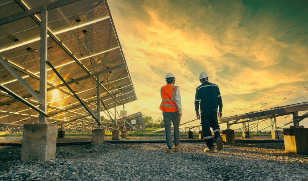 Low angle view of technician walks with investor through field of solar panels, Alternative energy to conserve the world's energy, Photovoltaic module idea for clean energy production.